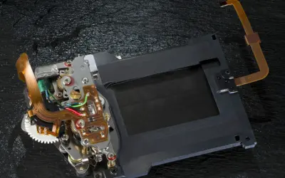 Mechanizm migawki szczelinowej aparatu z taśmami flex i elementami elektronicznymi.