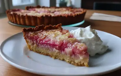 En bit rabarberpaj lchf med vispad grädde. Hela pajen syns i bakgrunden.