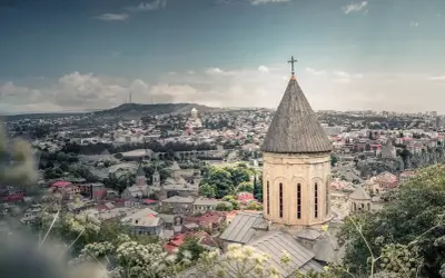 Widok na Tbilisi z kościołem w pierwszym planie. Marzysz o podróży? Sprawdź, ile trwa lot do Gruzji!