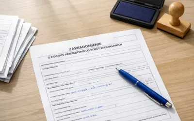 Formularz "Zawiadomienie o zamiarze przystąpienia do robót budowlanych" z niebieskim długopisem, stosem dokumentów i pieczątką.