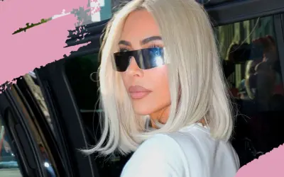 Frau mit platinblonden Haaren und futuristischen Sonnenbrillen steigt aus einem Auto.