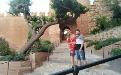 Pareja posando en escalinatas de piedra con un árbol retorcido y murallas de cañarete Almería de fondo.