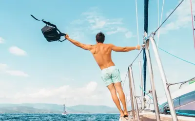 Uomo con zaino in barca a vela, un esempio di come vestirsi in barca a vela: costume e libertà.