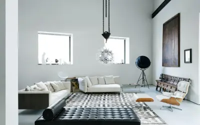 Soggiorno moderno con divani bianchi, chaise longue in pelle nera e un'iconica poltrona. Un ambiente che evoca case eleganti e raffinate.