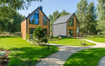 Nowe, nowoczesne domki w lesie nad morzem, otoczone zielenią i ścieżkami.