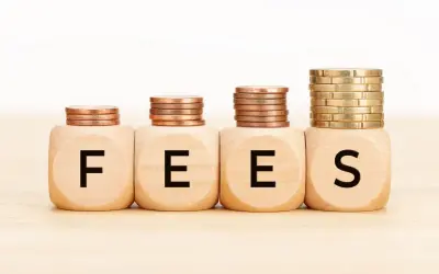 Cztery drewniane kostki z literami F, E, E, S tworzą napis FEES. Nad nimi piętrzą się monety, symbolizując rosnące opłaty.