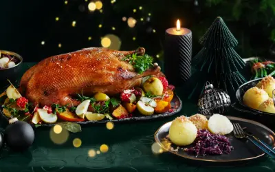 Festliches weihnachtsessen einen tag vorher vorbereiten: goldbraune Gans mit Früchten, Klößen und Rotkohl, Kerzenlicht und Weihnachtsdeko.