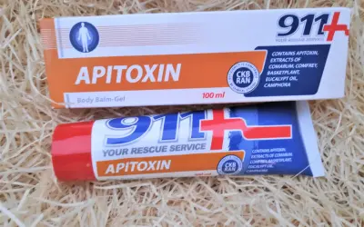 Dwa opakowania kremu z jadem pszczelim "Apitoxin" 911+ na tle słomy.