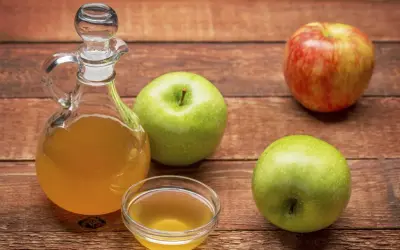 Apfelessig in einer Karaffe und Schale, daneben Äpfel. Vielseitige Apfelessig Anwendung für Küche und Gesundheit.