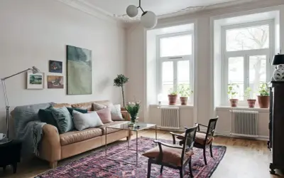 En vardagsrumsinredning som visar vad bohemisk betyder: en brun skinnsoffa, en stor mönstrad matta, konst och växter.