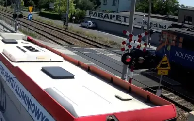 Autobus czeka na przejazd kolejowy w drodze do Częstochowy. Pociąg Kolprem mija przejazd.