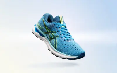 Scarpa da running Asics Gel Nimbus 24 uomo blu con dettagli gialli, in volo su sfondo sfumato.