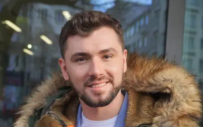 Uśmiechnięty Kamil Bednarek w futrzanej kurtce. Może właśnie wraca do swojej żony po koncercie.