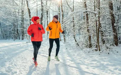 Un couple profite de l'air frais en courant sous la neige dans une forêt enneigée.