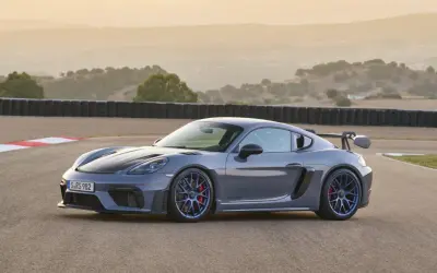 Szary Porsche GT4 RS na torze wyścigowym, z charakterystycznym skrzydłem i niebieskimi felgami.