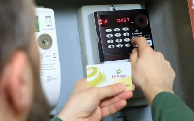 Doładowanie licznika PGE w weekend. Karta Energa w dłoni, wprowadzanie kodu na klawiaturze licznika.