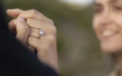 Delikatne pierścionki z diamentem, idealne jako pierścionki zaręczynowe. Biżuteria z diamentami na dłoni z jasnoróżowym manicurem.
