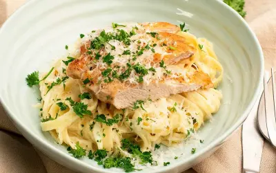 En krämig kyckling alfredo med tagliatelle, toppad med grillad kyckling, parmesan och färsk persilja. Ett perfekt recept för en snabb middag.
