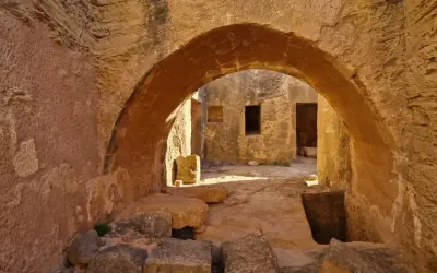 Kamienne łuki i korytarze w grobowcach królewskich Pafos, gdzie słońce rzuca długie cienie na starożytne mury.