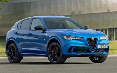 Niebieskie Alfa Romeo Stelvio z czarnymi felgami i czerwonymi zaciskami hamulcowymi. Sprawdź aktualną alfa romeo stelvio cena.