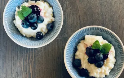 Två skålar med krämig risgrynsgröt, toppad med blåbär och mynta. Ett enkelt och gott risifrutti recept.