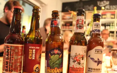 Fünf Flaschen Craft Beer stehen nebeneinander. Jede Flasche hat ein einzigartiges Etikett, das die Vielfalt von Craft Beer zeigt.