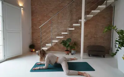 Donna in posizione rana yoga, con le ginocchia divaricate e il busto appoggiato sugli avambracci.