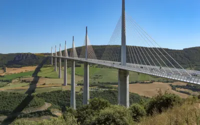 El viaducto de Millau, una maravilla de la ingeniería, se alza majestuoso sobre un valle verde. Su construcción desafía la gravedad.