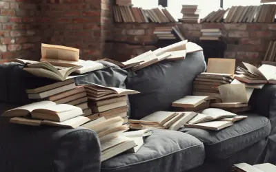 Stare książki na kanapie, stosy i otwarte tomy. Zastanawiasz się, gdzie oddać stare książki? Może biblioteka lub lokalna akcja charytatywna?