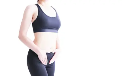 Femme en tenue de sport, mains sur le bas-ventre. Une solution pour la fuite urinaire pendant le sport.