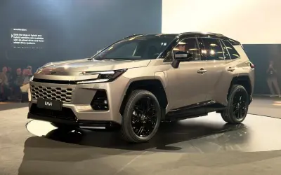 Nowy Toyota RAV4 2026 w kolorze szampańskim, z czarnymi felgami i przyciemnianymi szybami, prezentowany na scenie.