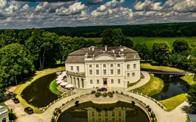 Pałac w Kurozwękach, otoczony fosą i parkiem, to wspaniałe atrakcje. Widać mostki, stawy i otaczający las.