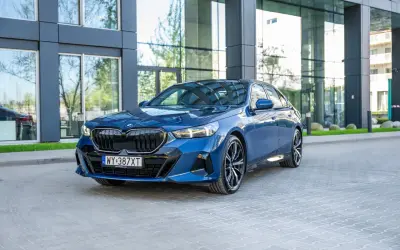 Eleganckie, granatowe BMW 540d z nowoczesnym designem, zaparkowane przed szklanym budynkiem.