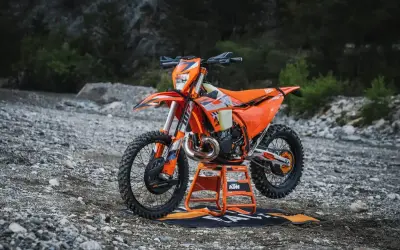 Pomarańczowy KTM EXC 300 2T na stojaku, gotowy do jazdy w terenie. Sprawdź jego dane techniczne!