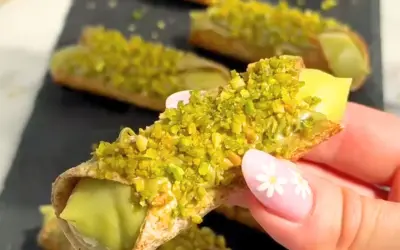 Chrupiące rurki wypełnione kremowym nadzieniem, obficie posypane zielonymi, aromatycznymi pistacjami. Te cannoli pistacjowe wyglądają niezwykle apetycznie.