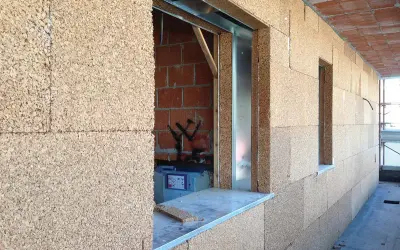 Blocchi di sughero, il miglior isolante termico naturale, rivestono le pareti di un edificio in costruzione, con aperture per finestre.