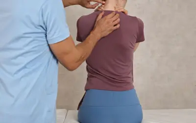 Fizjoterapeuta bada plecy pacjentki, która może mieć hiperlordozę.
