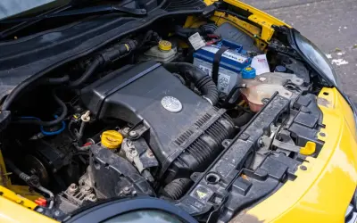 Silnik żółtego Alfa Romeo MiTo. Widoczny akumulator, obudowa filtra powietrza z logo marki i płyny eksploatacyjne.
