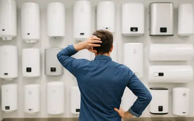 Mężczyzna zastanawia się, który bojler elektryczny 15l wybrać z wielu dostępnych modeli.