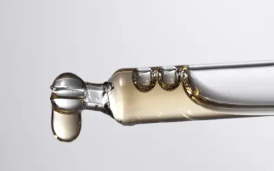 Tropfen eines goldenen Serums, das Bisabolol enthält, fallen aus einer Pipette.