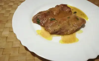 Due fettine di tacchino appetitose, immerse in una salsa dorata e profumata, servite su un piatto bianco.