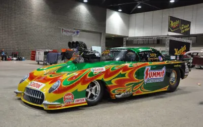 Une voiture de dragster aux couleurs vives, un exemple de tuning extrême, avec un moteur surdimensionné et des flammes peintes.
