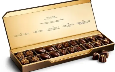 Caja abierta de chocolates finos, "la chuche más cara del mundo", con descripciones de sabores inspirados en elementos naturales.
