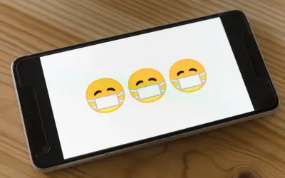 Trzy emoji w maseczkach na ekranie smartfona. Dowiedz się, jak usunąć wirusy z iPhone.