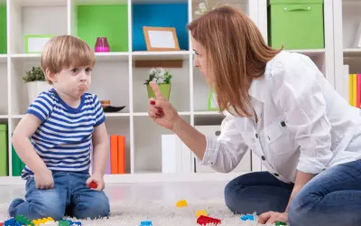 Mamma che si arrabbia con i figli piccoli, puntando il dito contro il bambino che fa il broncio.