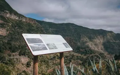 Panel informativo en el mirador de Carboneras, con vistas a un valle montañoso cubierto de vegetación.