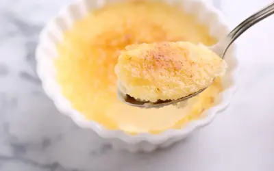 Une cuillère de semoule au lait et aux œufs, avec sa croûte caramélisée dorée, prête à être dégustée.