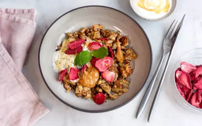 En skål med granola, yoghurt, jordnötssmör, torkade jordgubbar och mynta. En perfekt nyttig frukost för en bra start på dagen.