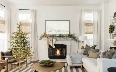 Cozy living room with a lit Christmas tree and fireplace, showcasing elegant holiday mantel ideas with stockings and greenery.