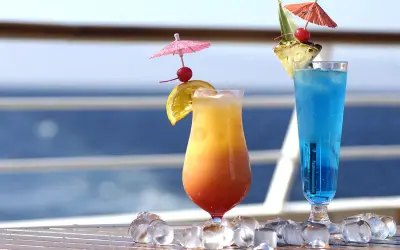 Due cocktail colorati, un tramonto e un blu intenso, decorati con ombrellini e frutta, perfetti per godersi i pacchetti bevande MSC in crociera.